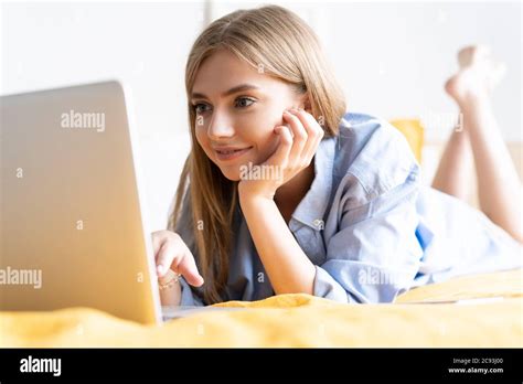 A Smiling Woman Lying Down The Bed In Front Of Her Laptop Working From Home In Quarantine