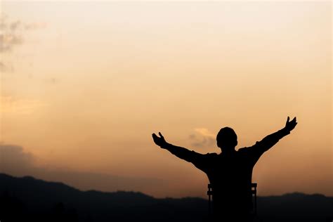 Silhouette Of A Man Lift Hands Up And Prayer And Worship God At Sunset