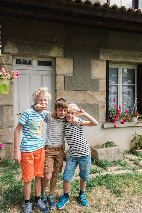 Happy Boys In Striped Shirts Hugging And Smiling By Stocksy