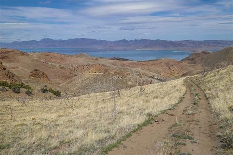 A Backcountry Dirt Road Descends Toward A Scenic Distant Lake Stock