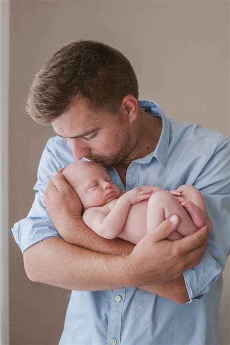 Father Holding His Newborn Baby In His Arm Hugging And Kissing Her By Stocksy Contributor Lea