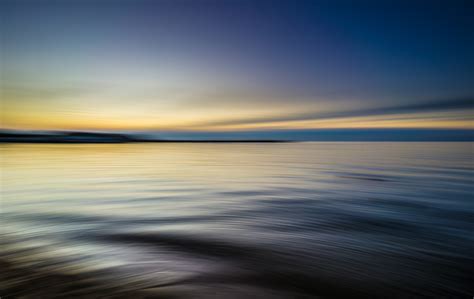 Tranquil Rippling Waters Reflect A Blue And Yellow Sky At Sunset Water