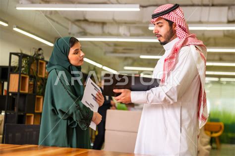 رجل اعمال سعودي و سيدة اعمال سعودية مجتمعان سويا داخل مقر الشركة ، ادارة الاعمال و المهام في