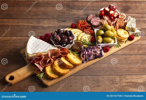 A Savoury Charcuterie Board Covered In Meats Olives Peppers Berries And