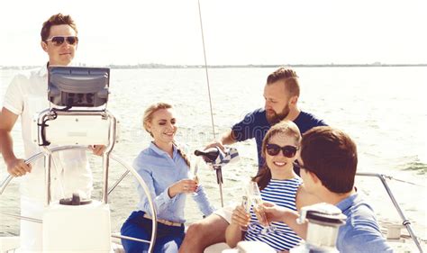 Group Of Happy Friends Having A Party On A Yacht And Drinking Ch
