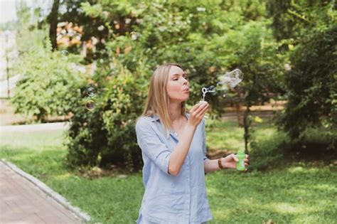 Premium Photo Young Woman Blowing Bubbles In The Park And Having Fun