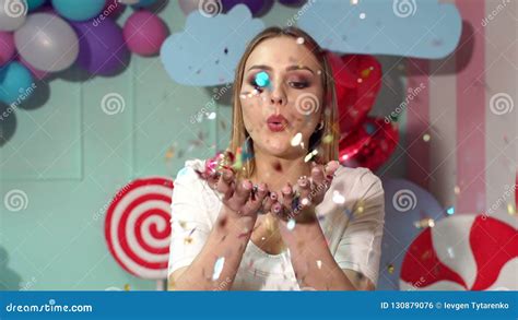 A Happy Girl Blows On A Tinsel Or Confetti In A Room With Huge Sweets