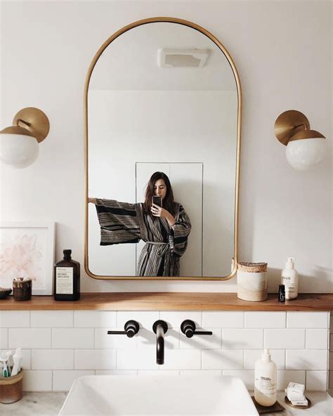 a woman taking a selfie in front of a bathroom mirror while holding a towel