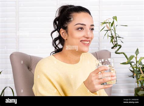 Smiling Young Woman Holding Glass Of Pure Water Looking Aside Happy