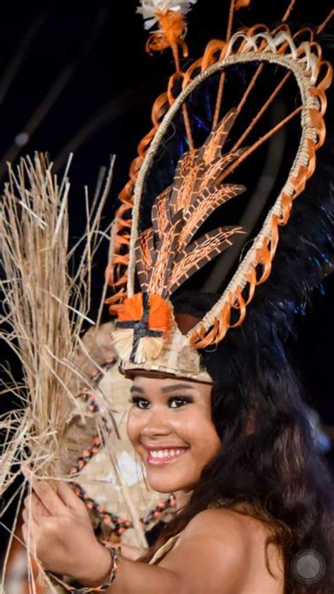A Woman In An Elaborate Headdress Smiles At The Camera While Holding A Fan