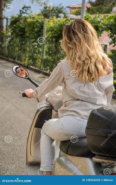 Young Charming Girl With Long Hair Rides A Motorcycle And Looks At Her