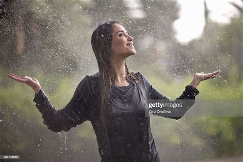 Drenched Young Woman With Arms Open In Rainy Park Bildbanksbilder