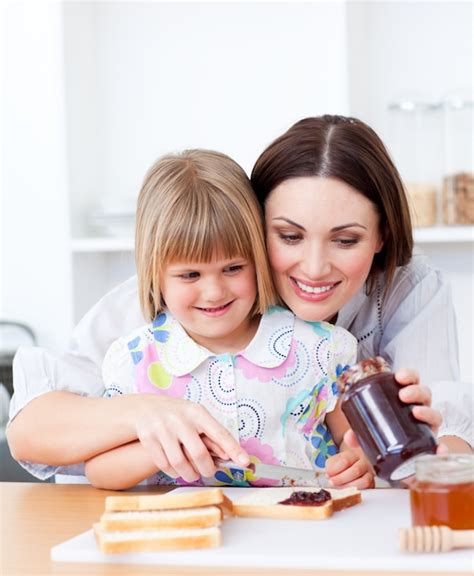 Madre Sonriente Que Ayuda A Su Hija A Preparar El Desayuno Foto Premium