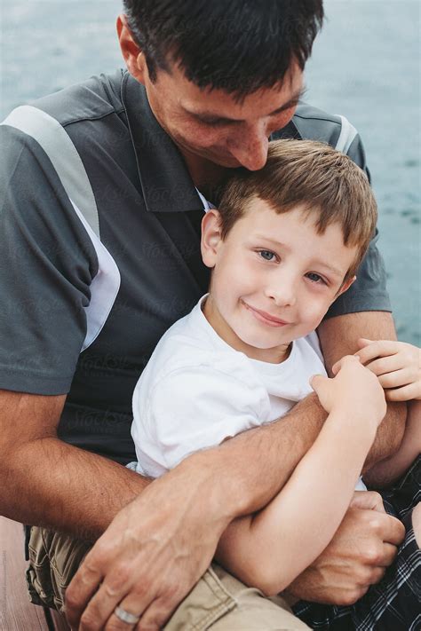 Father And Son Smiling And Cuddling At The Lake By Stocksy