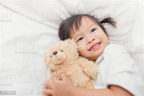 Asian Cute Little Child Girl Hugging Teddy Bear In Bed Stock Photo