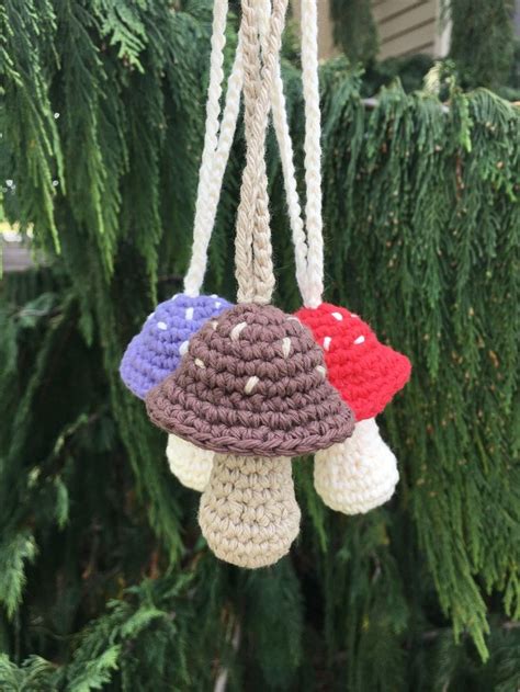 Three Crocheted Mushrooms Hanging From A Tree