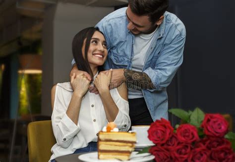 Boyfriend Hugging Girlfriend Making Surpirse And Giving Bouquet In Cafe