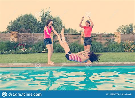 Group Of Teenage Girlfriends Having Fun In Swimming Pool Play Throwing Each Other In The Pool