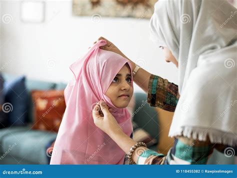 Muslim Mother Putting On A Hijab On Her Little Daughter Stock Photo