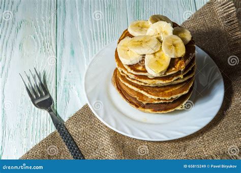 Stack Of Homemade Pancakes With Banana Slices And Honey On White Plate