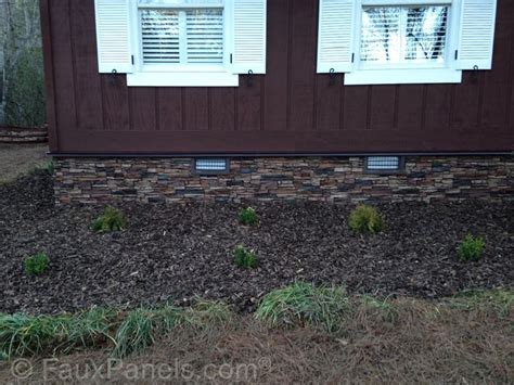 The Side Of A House With Grass Growing In Front Of It And Two Windows