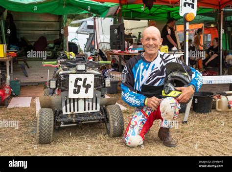 Leon Clark, a racing lawn mower driver kneels next to his racing mower