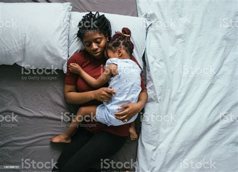 Top View Of Beautiful Mother With Little Daughter Sleeping In Bed Stock