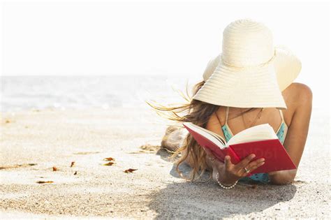 Young Woman Sunbathing And Reading Book On Beach Malibu California