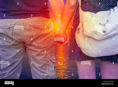 Young Couple Holding Hands On Beach At Sunset Stock Photo Alamy