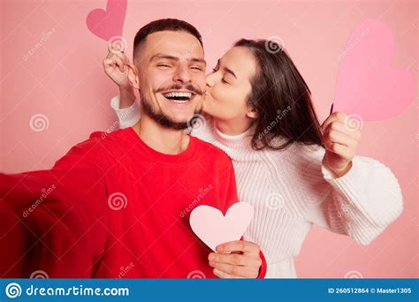 Portrait Of Lovely Young Couple Woman Kissing Happy And Smiling Man Taking Selfie Together