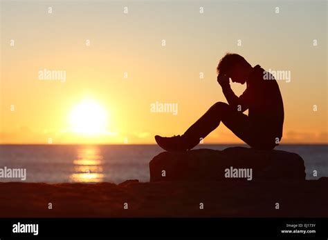 Sad Man Silhouette Worried On The Beach At Sunset With The Sun In The