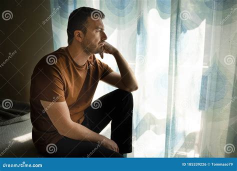 Portrait Of One Guy Feeling Sad And Looking Through Window Stock Photo