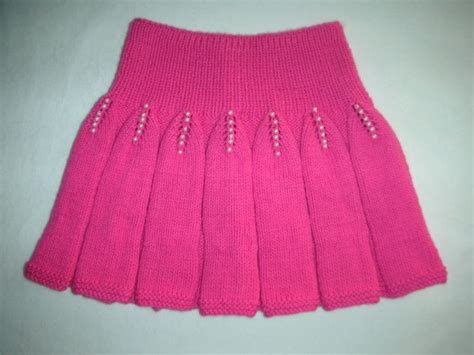 A Pink Knitted Skirt With Beading On The Bottom And Side Sitting On A White Surface