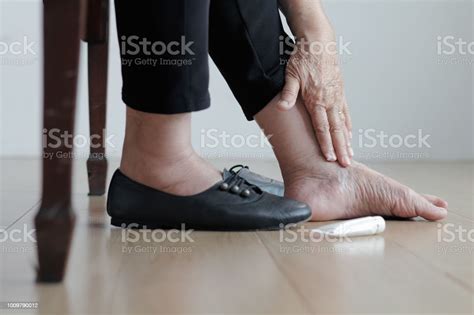 Elderly Woman Putting Cream On Swollen Feet Before Put On Shoes Stock