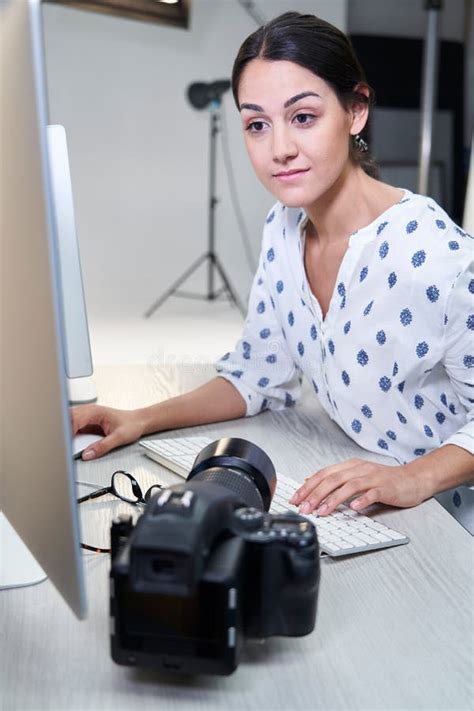 Female Photographer In Studio Reviewing Images From Photo Shoot On