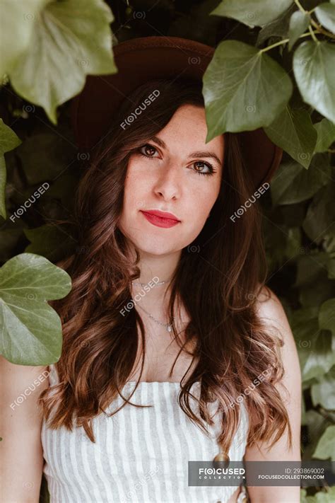 Attractive Long Haired Woman In Hat Thoughtfully Looking At Camera