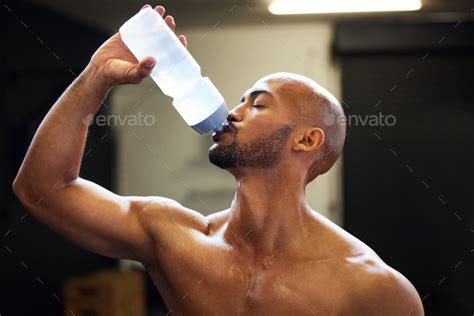 Shot Of A Muscular Young Man Drinking Water While Exercising In A Gym