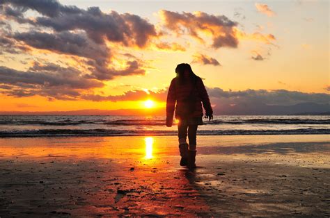 Person Wearing Coat Standing On Sea Side Facing The Sun At Sea Hd