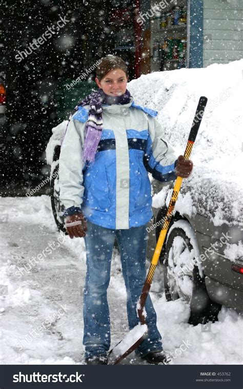 Teen Girl With Shovel Standing In Snow Storm Stock Photo