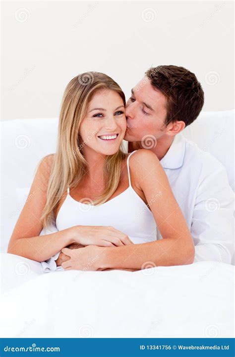 affectionate man kissing his wife sitting on bed royalty free stock image image 13341756