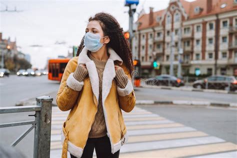 beautiful afro haired woman wearing protective medical face mask stand on the street of city