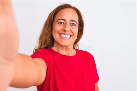 middle age mature woman taking a selfie photo using smartphone over isolated background with a