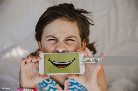 Young Girl Pulling A Funny Face With Smartphone Over Her Mouth High Res
