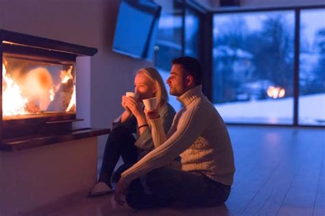 Premium Photo Young Romantic Couple Sitting On The Floor In Front Of Fireplacetalking And