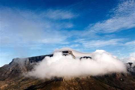 A Fluffy Cloud Enveloping A Rocky Mountaintop On A Bright Day Cloud