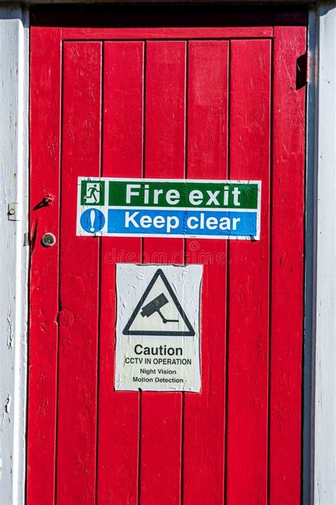 Fire Exit And Keep Clear Sign On A Red Painted Wooden Door With No
