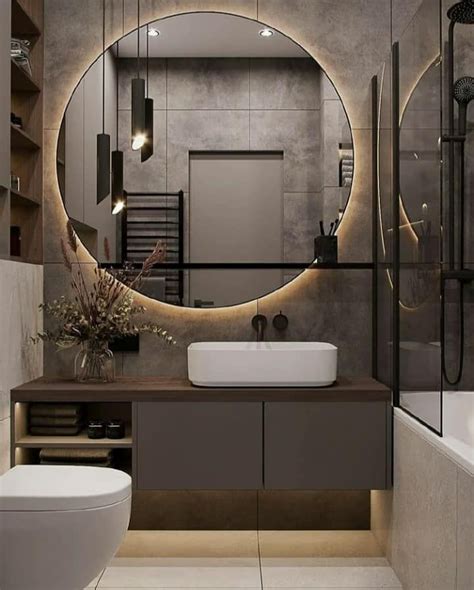 A Modern Bathroom With A Round Mirror Above The Sink