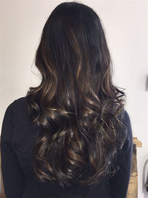 Trendy 40 year old woman with long curly hair in elegant black swimsuit on a white. Dark sun kissed balayage | Balayage