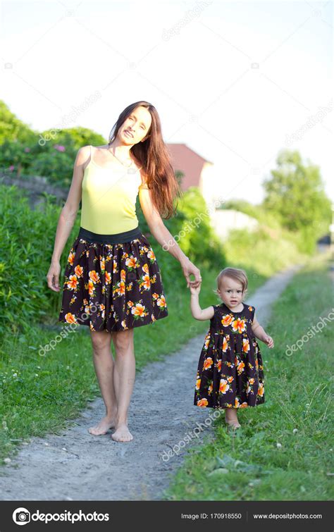 Mom And Baby Girl Walking Barefoot On A Country Road In The Same Dress