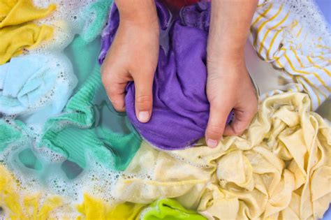 If your brights are brand new, wash them separately for the first few washes to help keep them from bleeding dye onto other clothes. Female hands wash colored clothes in basin. Photo ...